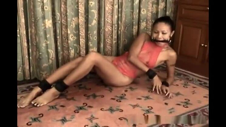 赤いランジェリーを着たスリムなアジア人女性が手錠をかけられ、猿ぐつわをされている